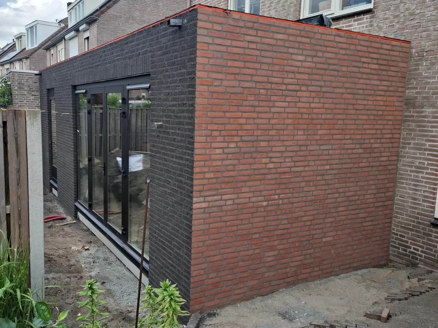 Hoek van een aanbouw met twee steensoorten in verstek gezaagd en een donkere voeg