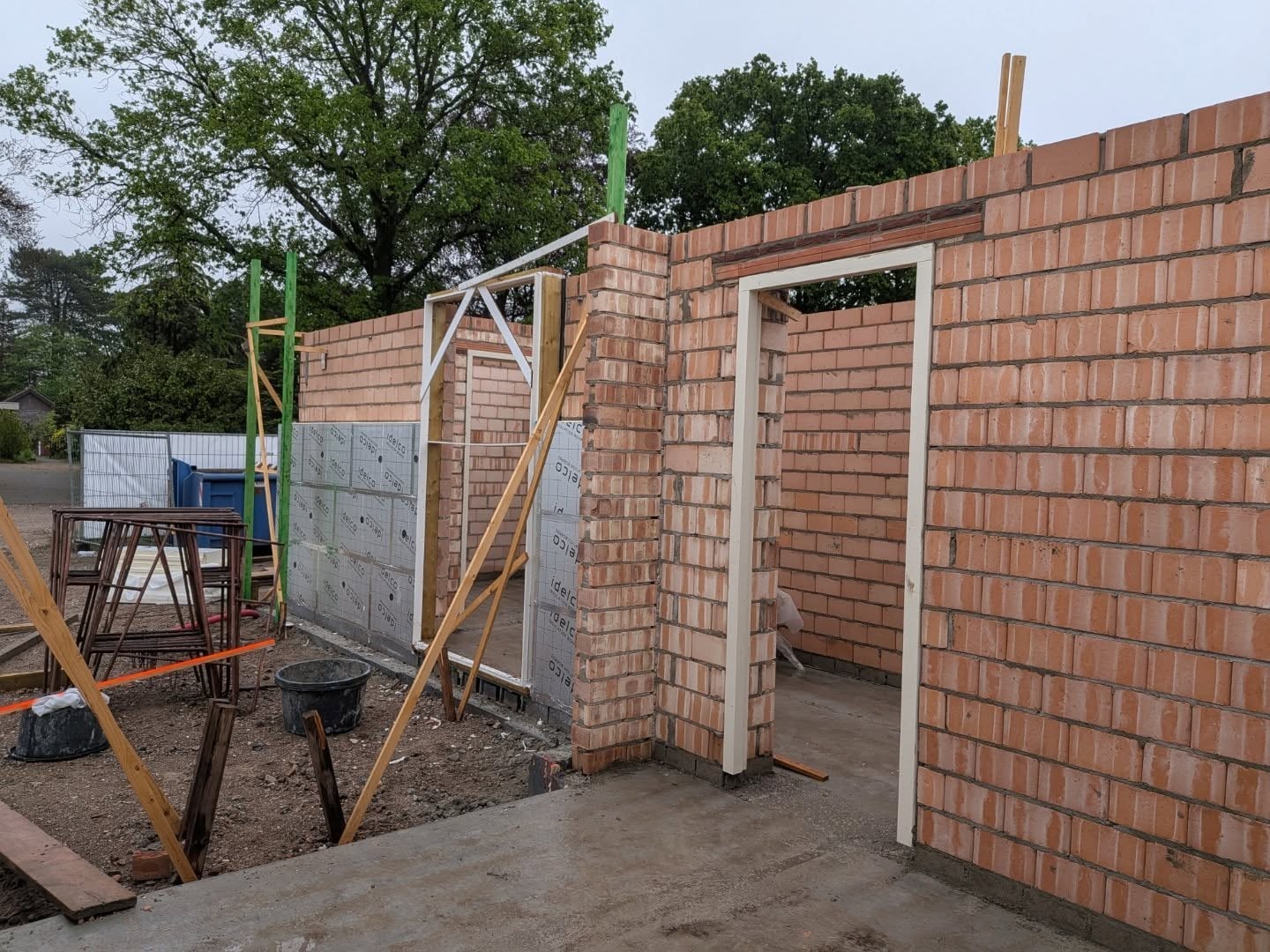 Vers gemetselde binnenmuren in lichtrode steen met een deuropening op een bouwplaats